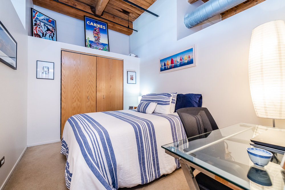 1250 West Van Buren Street, Unit 703 Chicago, IL 60607 - Photo 6 of 18 a bedroom with a bed and wooden floor