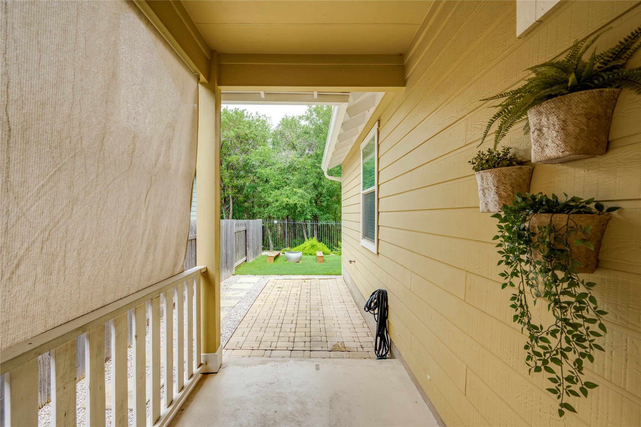 6008 Whipple Way Austin, TX 78745 - Photo 31 of 39 A quaint covered patio opens to a stone-paved walkway leading to a fenced yard with lush greenery.
