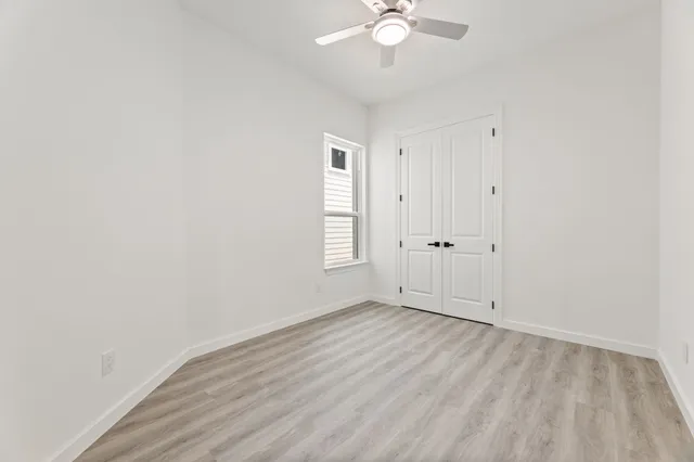 a view of an empty room with a window and wooden floor