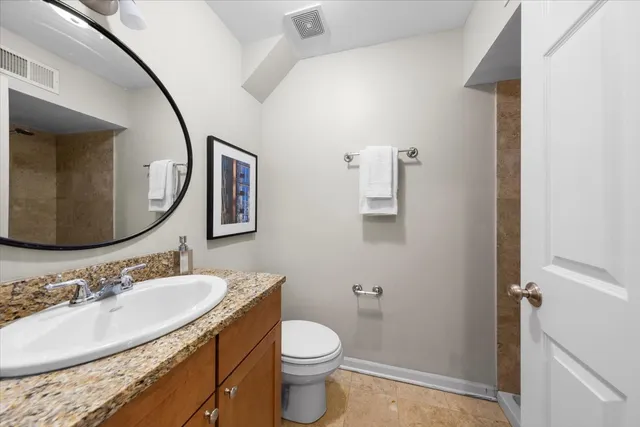 a bathroom with a granite countertop sink toilet and mirror