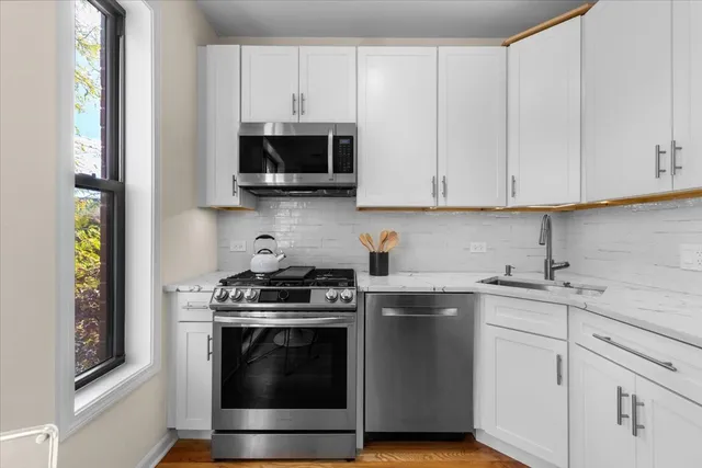 a kitchen with stainless steel appliances granite countertop white cabinets and a stove