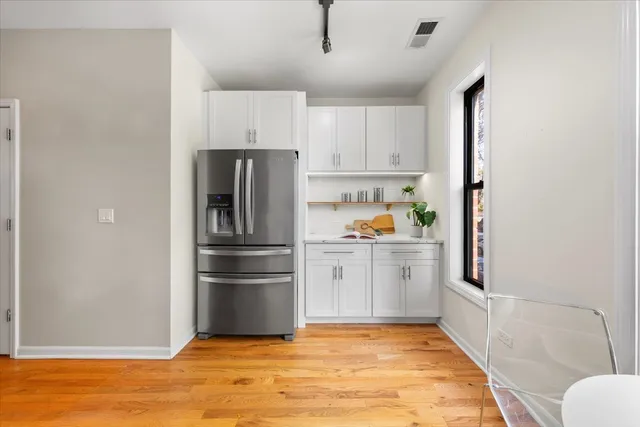 a kitchen with a refrigerator and white cabinets