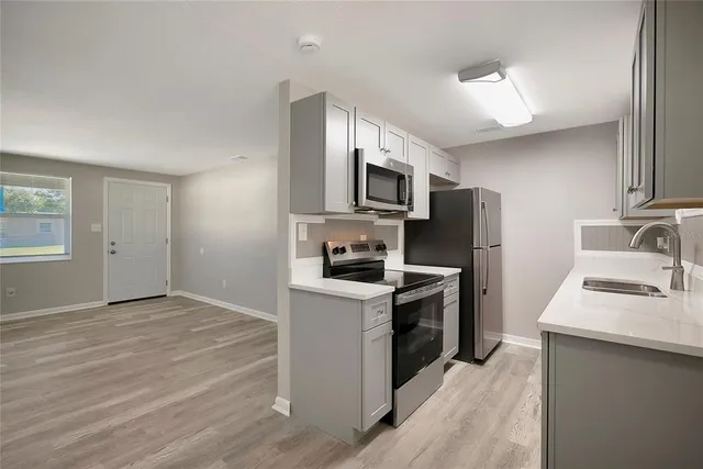 a kitchen with a sink a stove top oven and refrigerator