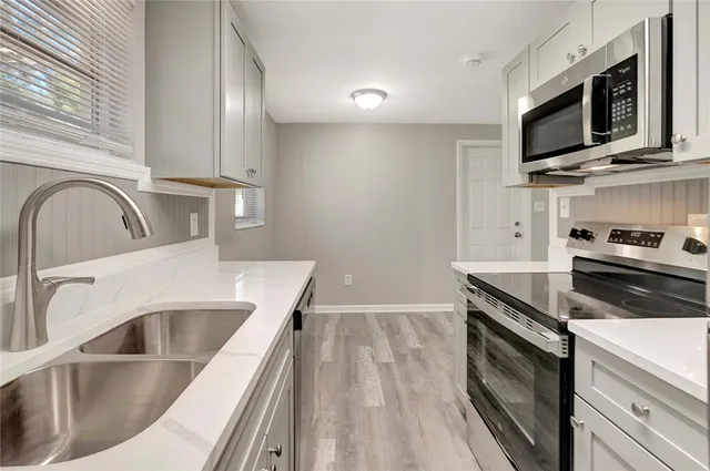 a kitchen with stainless steel appliances granite countertop a sink a stove and microwave