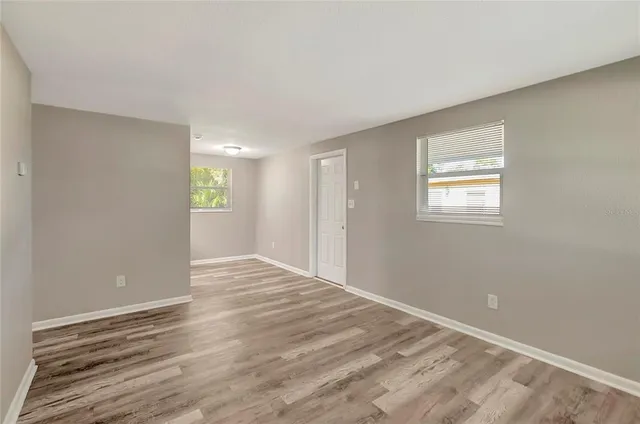 a view of an empty room with wooden floor and a window