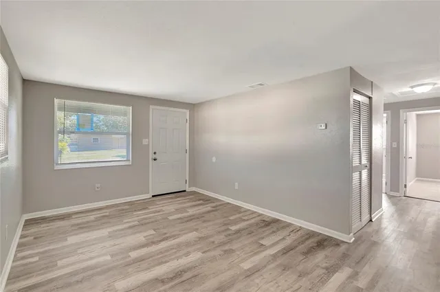 a view of an empty room with wooden floor and a window