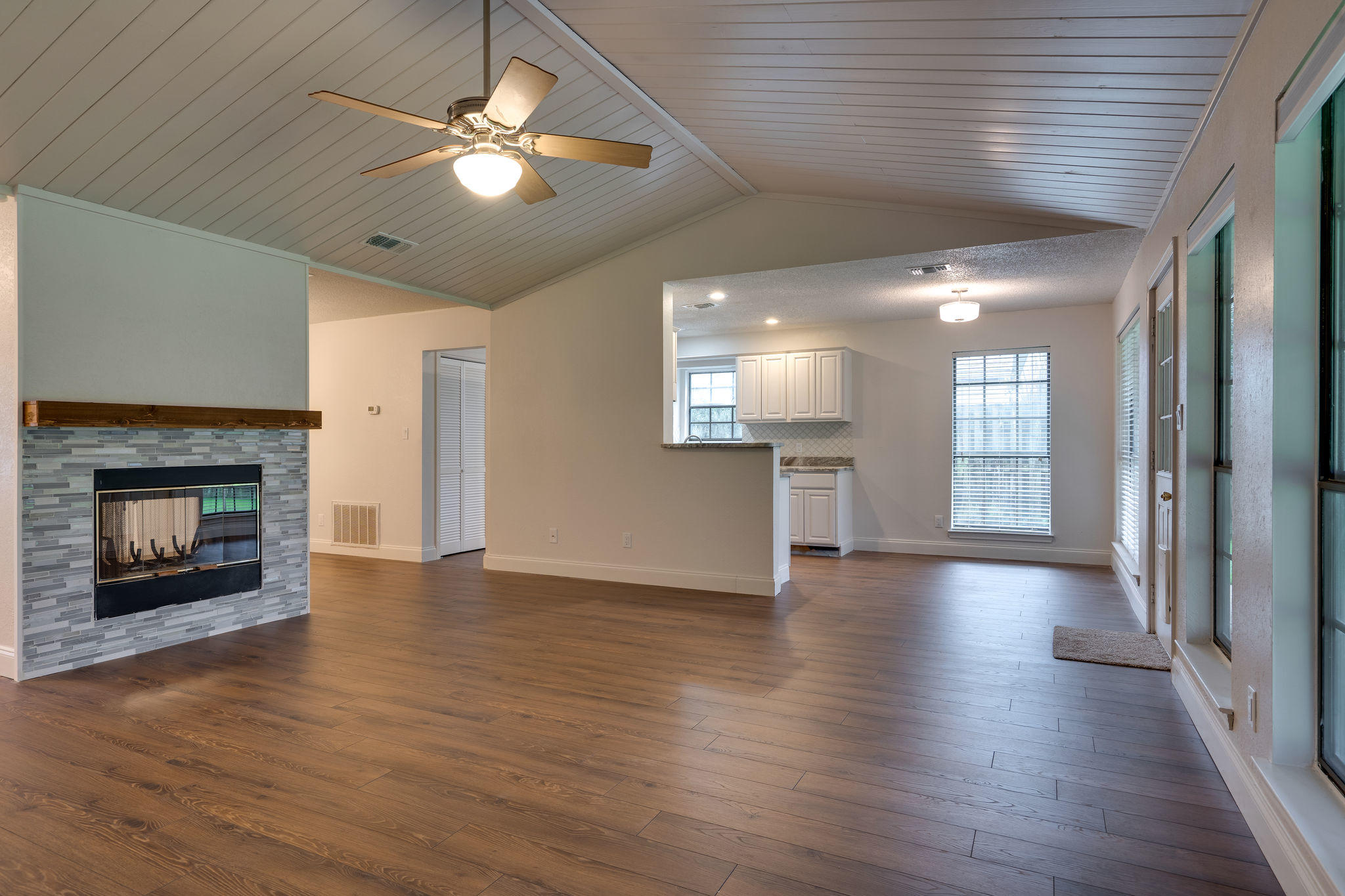 409 Juniper Street Destin, FL 32541 - Photo 8 of 32 an empty room with wooden floor a ceiling fan a fireplace and windows