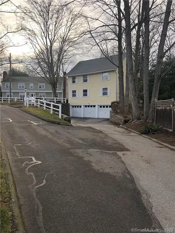 a view of a house with a large tree and wooden fence