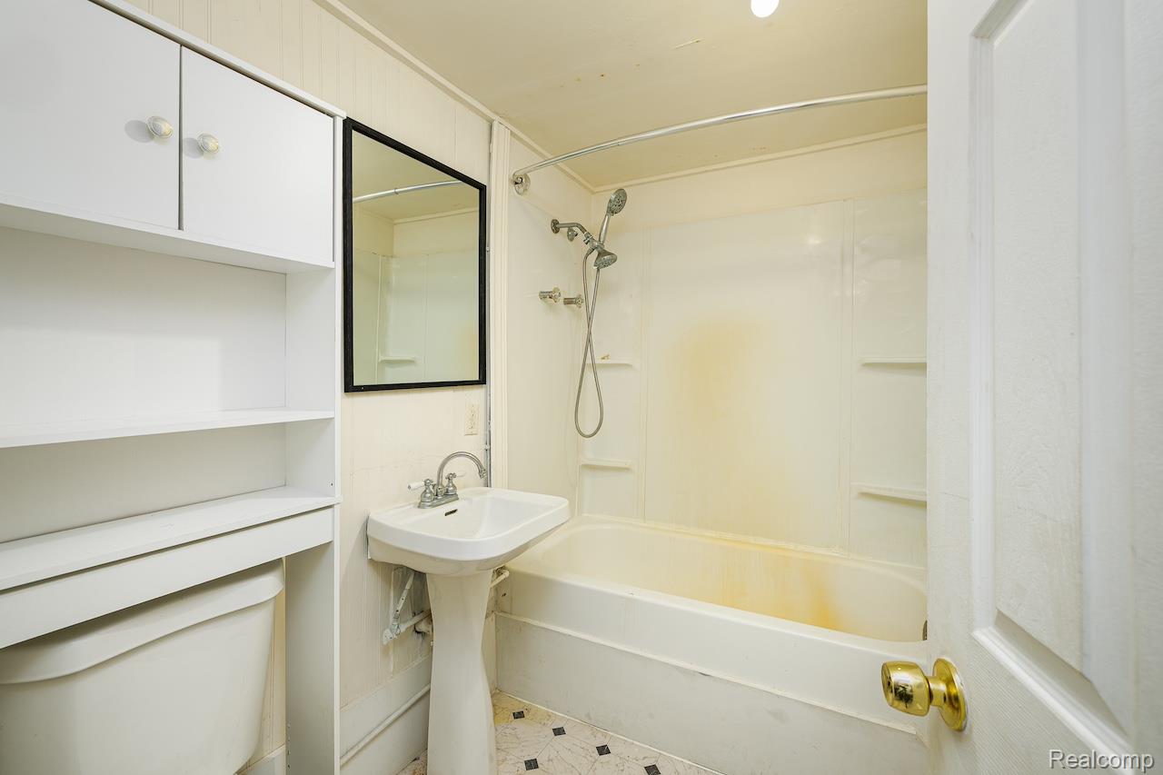 8595 Orchard Road Pinckney, MI 48169 - Photo 10 of 25 Pedestal sink with chrome fixtures, framed mirror, built-in white cabinetry, and a full bathtub with shower kit