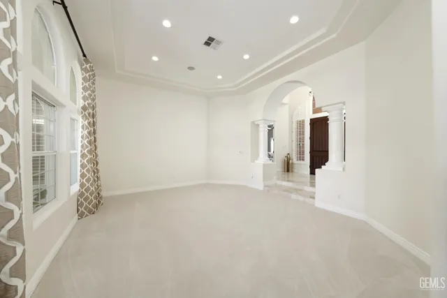 a spacious bedroom with a bed a mirror on dresser and a chandelier