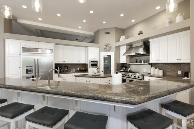 a kitchen with stainless steel appliances granite countertop a sink refrigerator and cabinets