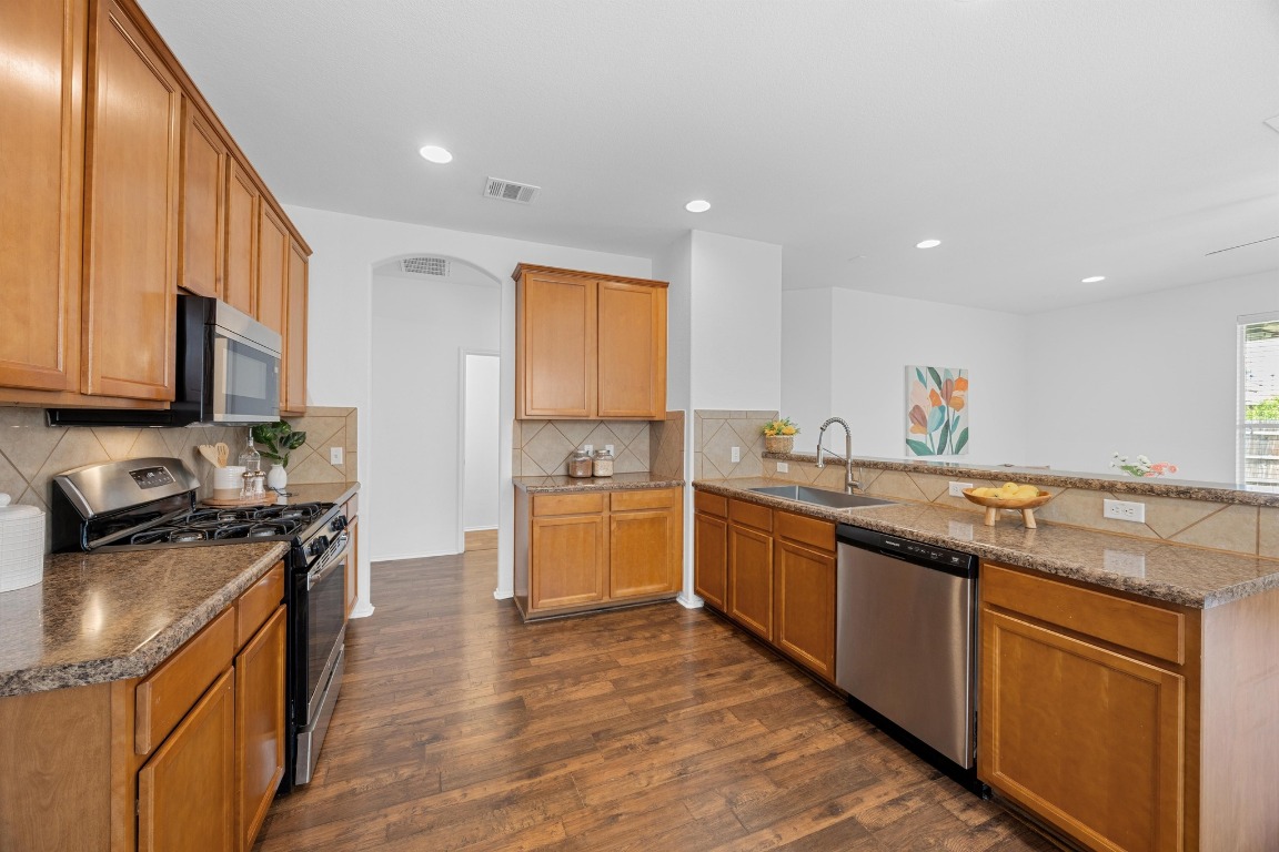 3612 Raven Caw Pass Pflugerville, TX 78660 - Photo 15 of 40 a kitchen with stainless steel appliances granite countertop a sink stove and refrigerator