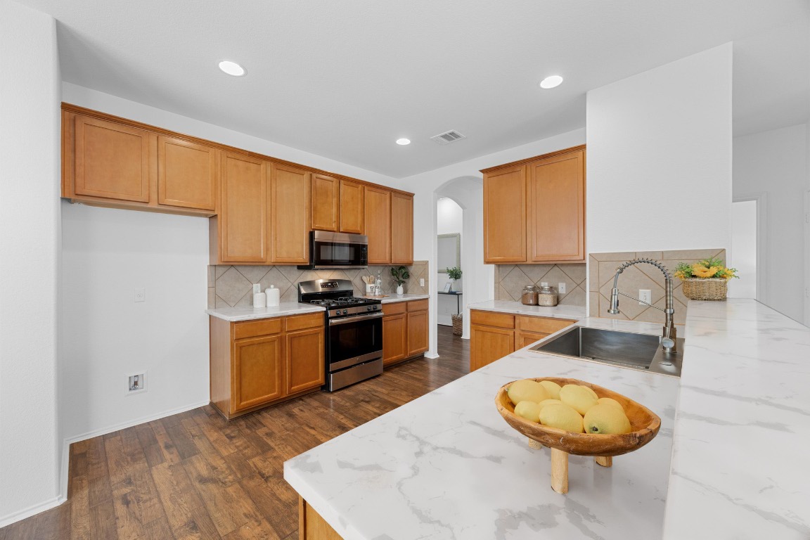 3612 Raven Caw Pass Pflugerville, TX 78660 - Photo 7 of 40 a kitchen with stainless steel appliances granite countertop a sink a stove and a refrigerator