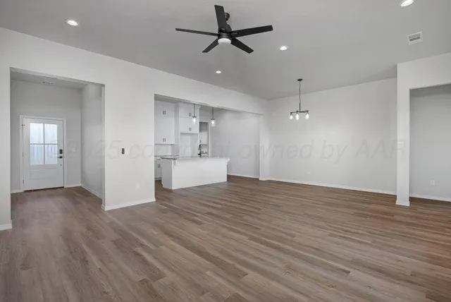 a view of a livingroom with a ceiling fan wooden floor and a ceiling fan