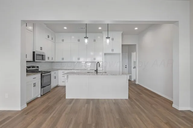 a large white kitchen with kitchen island a sink stainless steel appliances and cabinets