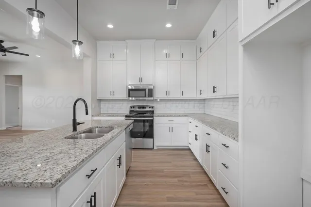 a kitchen with granite countertop white cabinets and appliances