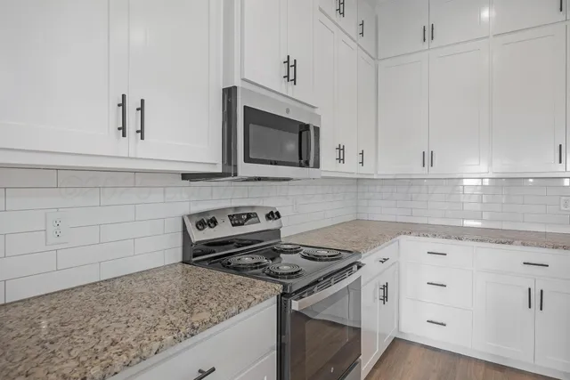 a kitchen with granite countertop white cabinets and stainless steel appliances