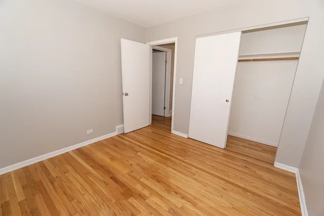 a view of an empty room with wooden floor and a closet