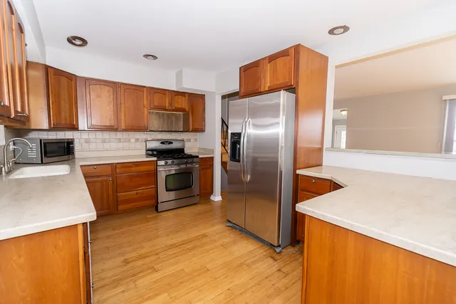 a kitchen with granite countertop a refrigerator a sink a stove and oven