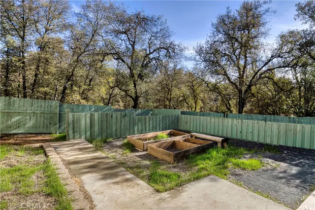 a view of backyard with wooden fence and large trees