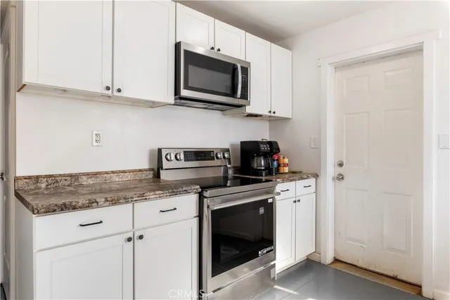 a kitchen with stainless steel appliances granite countertop white cabinets and a stove top oven