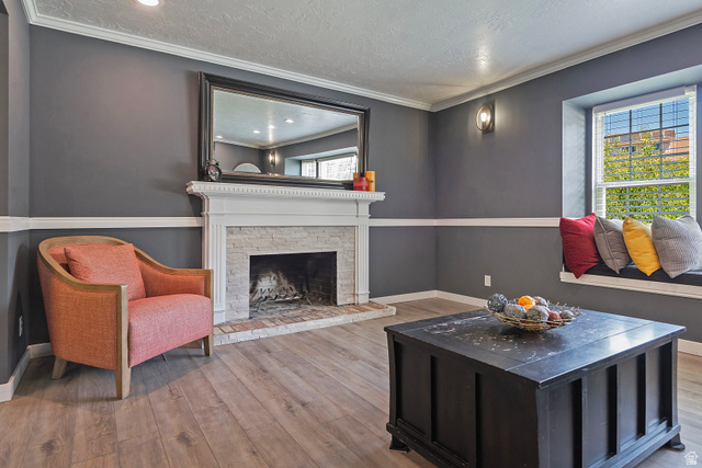 3310 Creek Road Salt Lake City, UT 84121 - Photo 10 of 49 Living area featuring a white mantel fireplace with a stacked stone surround and brick hearth, a built-in window seat, wood-finish flooring, recessed lighting, and wall sconces