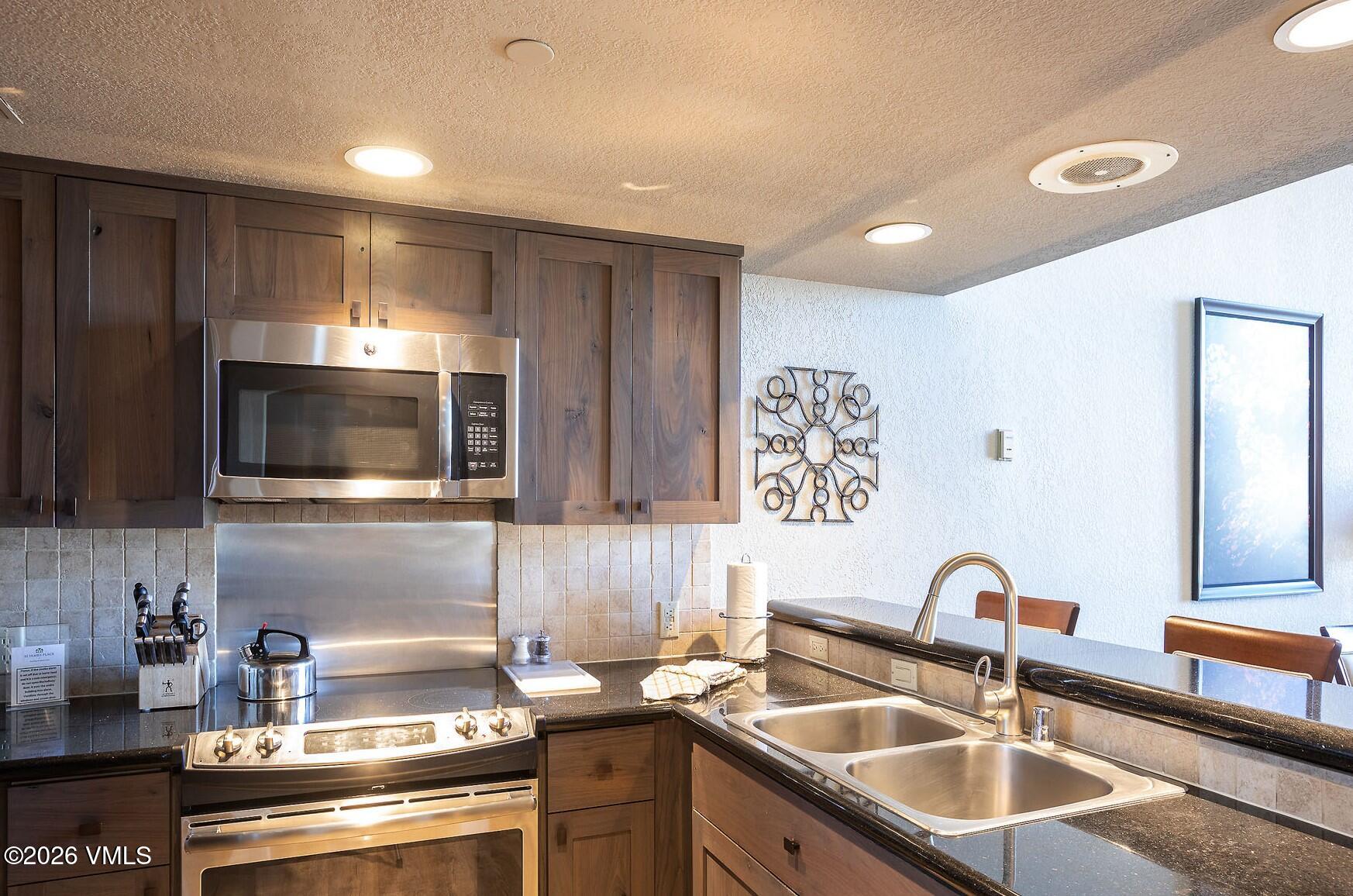 210 Offerson Road, Unit 41428 Beaver Creek, CO 81620 - Photo 6 of 25 a kitchen with kitchen island a sink stainless steel appliances and cabinets