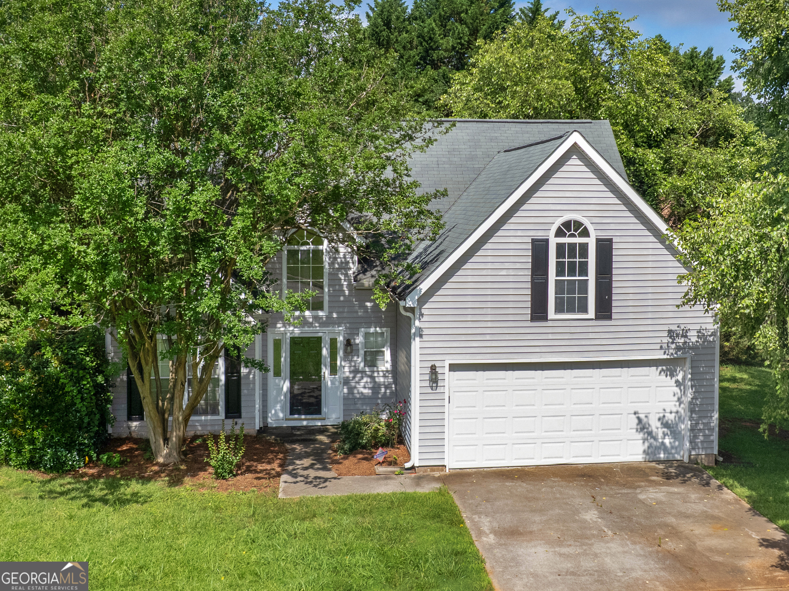 a view of a house with a yard and large tree