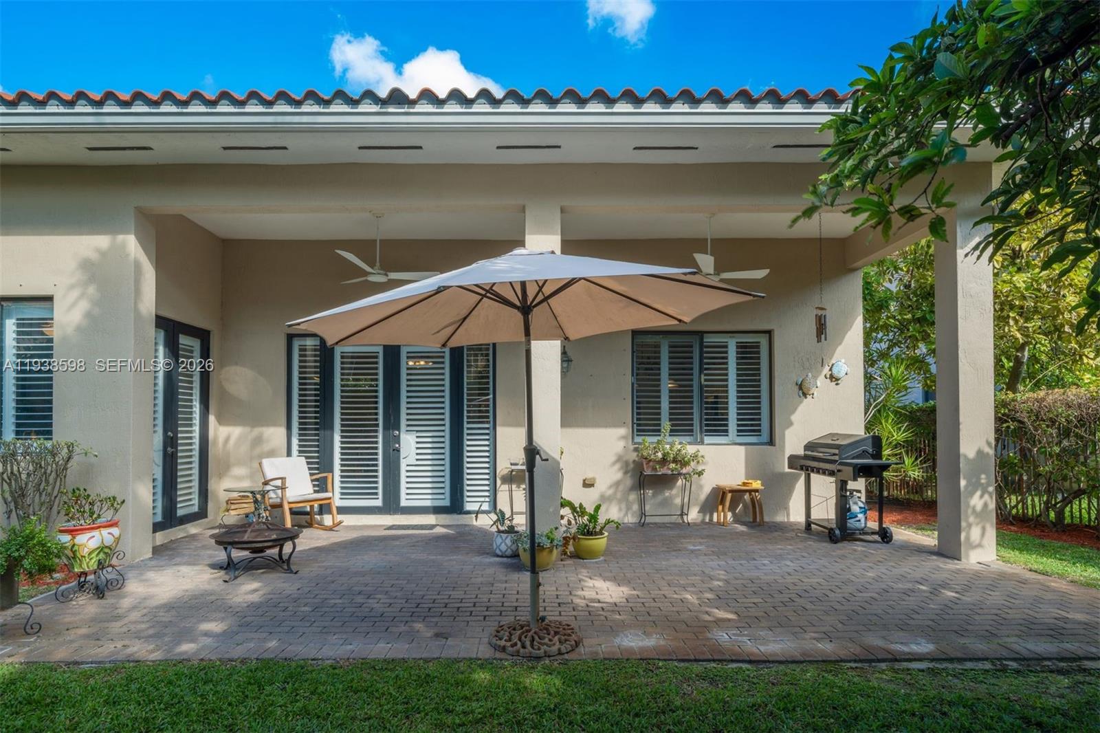 7548 Southwest 190th Street Cutler Bay, FL 33157 - Photo 34 of 53 a backyard of a house with table and chairs and potted plants