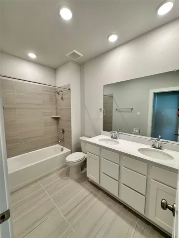 a bathroom with a double vanity sink toilet mirror and bathtub