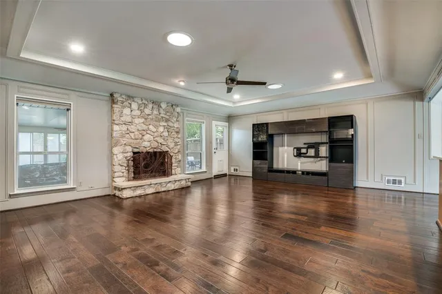 an empty room with wooden floor fireplace and windows