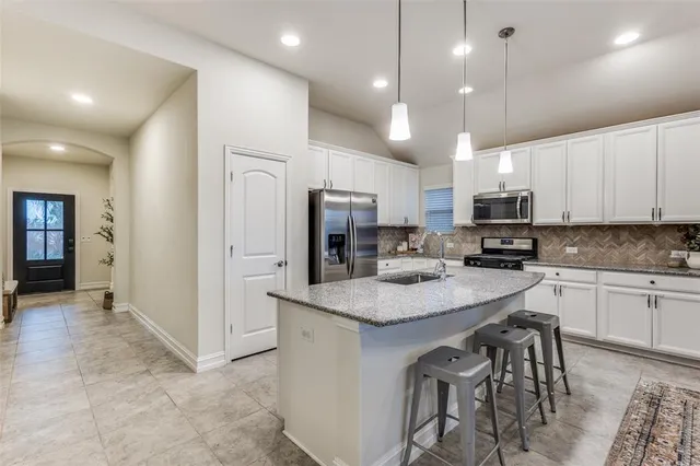 a kitchen with kitchen island granite countertop a sink cabinets and refrigerator