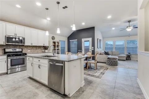 a large kitchen with stainless steel appliances lots of white cabinets