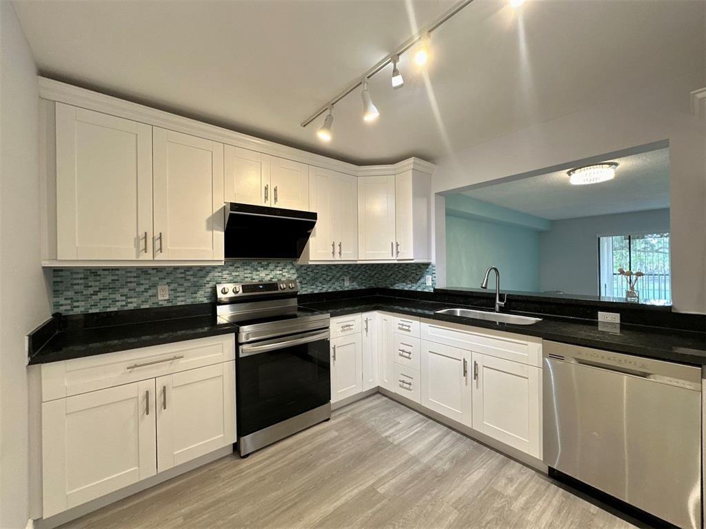 a kitchen with granite countertop white cabinets and black appliances