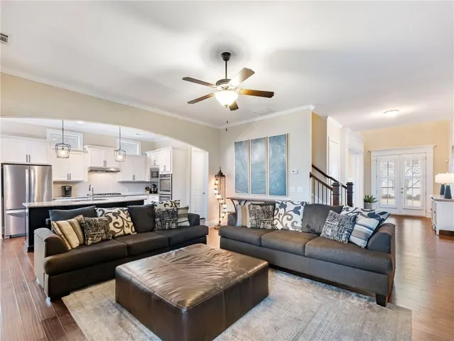 a large kitchen with stainless steel appliances kitchen island granite countertop a refrigerator a stove a sink dishwasher a dining table and chairs with wooden floor