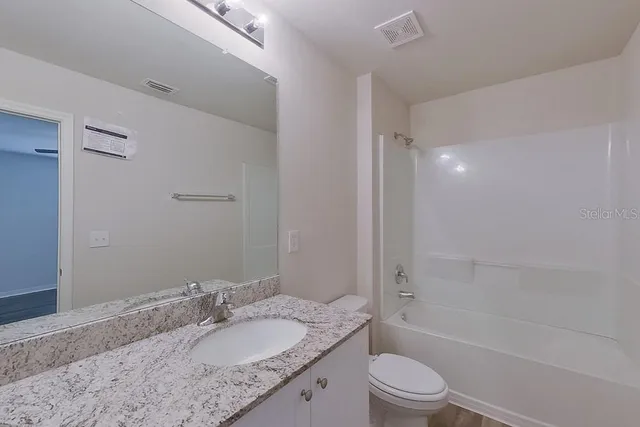 a bathroom with a granite countertop sink a toilet and shower