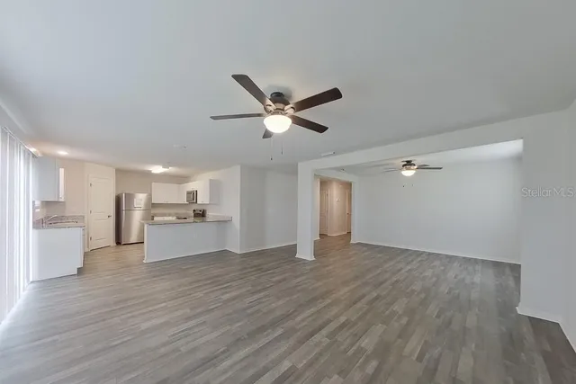a view of empty room with wooden floor and ceiling fan