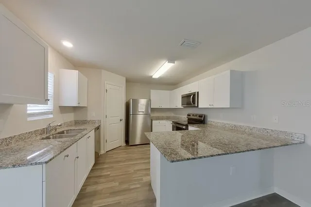 a large kitchen with granite countertop counter space a sink and stainless steel appliances