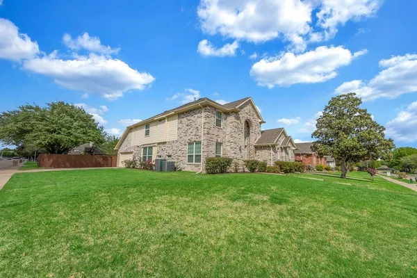 a view of a big house with a big yard and large trees