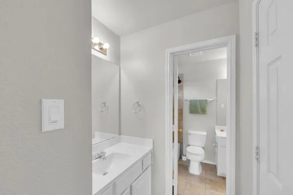 a bathroom with a granite countertop toilet a sink and a mirror