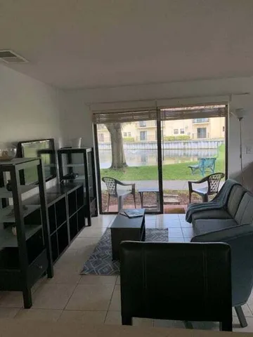 a living room with furniture tv and large windows