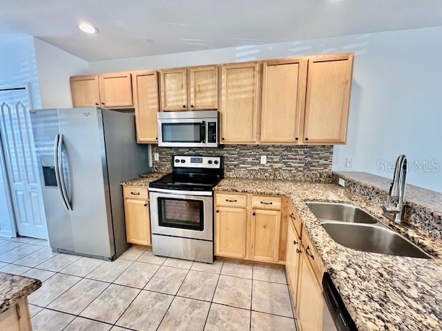 15609 Stable Run Drive Spring Hill, FL 34610 - Photo 9 of 37 a kitchen with stainless steel appliances granite countertop a stove a sink dishwasher a refrigerator and microwave