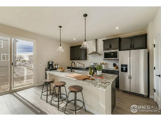 a kitchen with stainless steel appliances kitchen island granite countertop a refrigerator a stove a sink dishwasher with a dining table and chairs