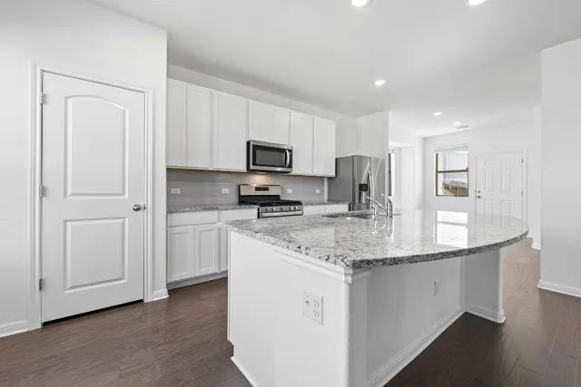 a kitchen with kitchen island granite countertop a sink white cabinets and stainless steel appliances