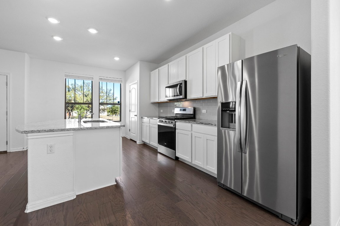 2429 Acoma Lane Leander, TX 78641 - Photo 5 of 39 a kitchen with granite countertop stainless steel appliances a refrigerator cabinets and wooden floor