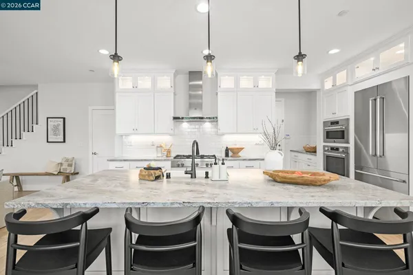 a kitchen with granite countertop a dining table chairs sink and refrigerator