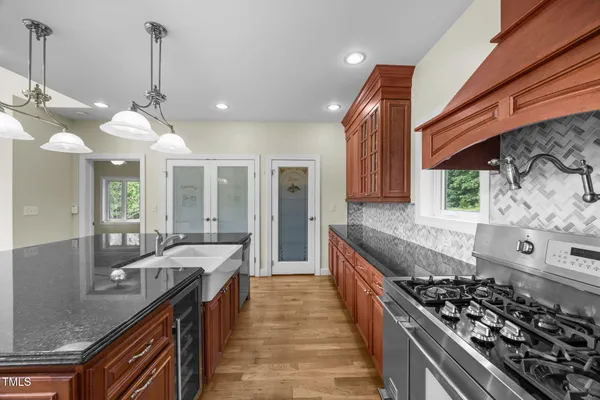 a kitchen with stainless steel appliances granite countertop a sink a stove and a wooden floors