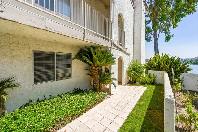 a front view of a house with a garden and lake view