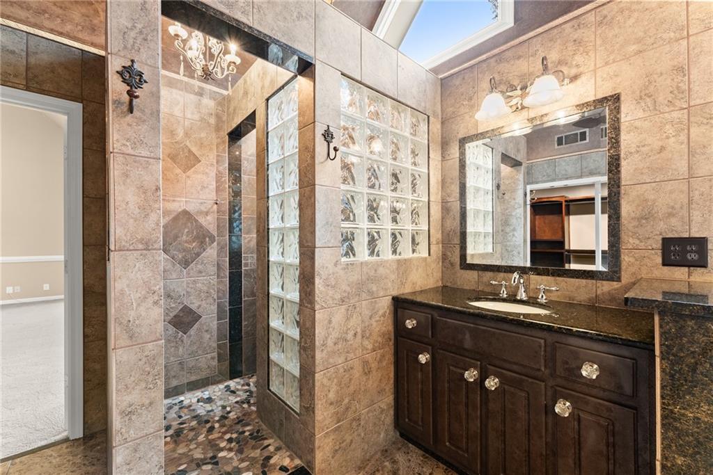 4863 Rosemoore Court Suwanee, GA 30024 - Photo 35 of 74 a bathroom with a granite countertop shower a sink and a mirror