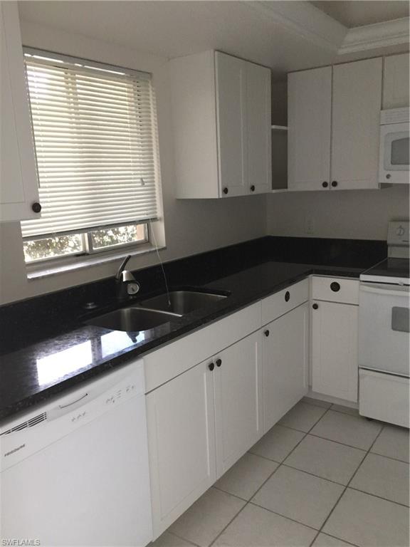 5651 Rattlesnake Hammock Road, Unit C108 Naples, FL 34113 - Photo 3 of 14 a kitchen with granite countertop white cabinets and sink